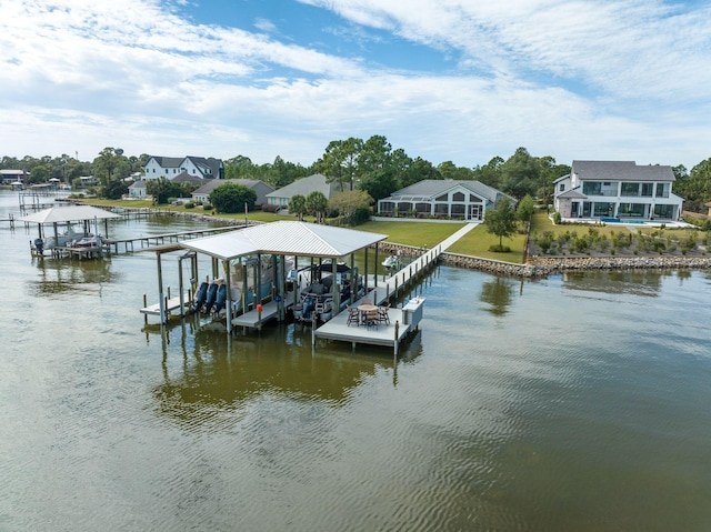 dock area with a water view, boat lift, and a yard