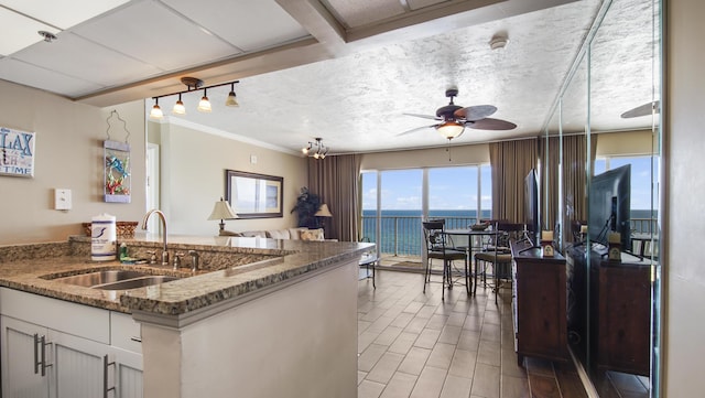 kitchen with a textured ceiling, light wood-style flooring, ceiling fan, dark stone counters, and a sink