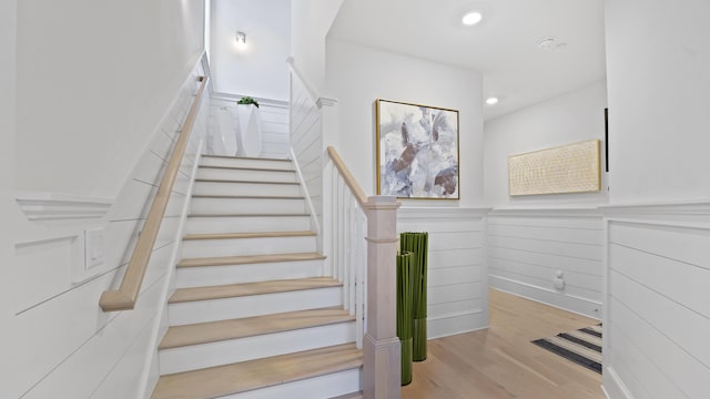 staircase featuring recessed lighting, wainscoting, and wood finished floors