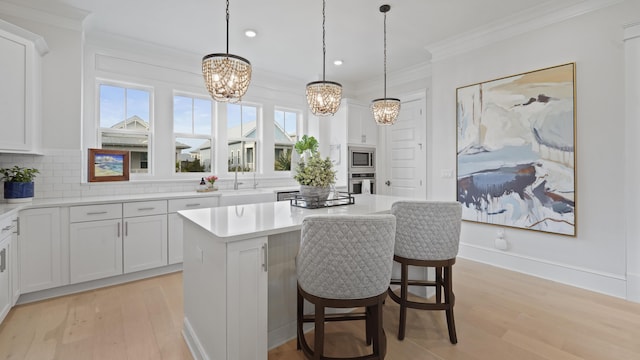 kitchen featuring a chandelier, stainless steel appliances, light wood-style floors, and ornamental molding
