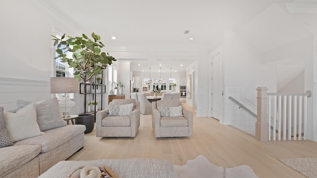 living room with crown molding, recessed lighting, visible vents, and light wood-style floors