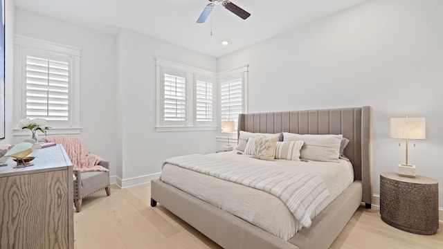 bedroom with baseboards, a ceiling fan, multiple windows, and light wood finished floors