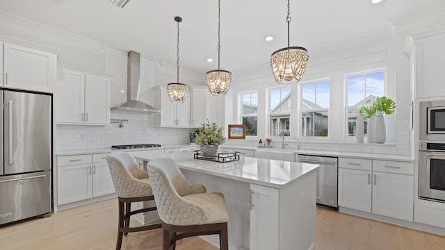 kitchen with decorative backsplash, a chandelier, stainless steel appliances, a kitchen island, and wall chimney exhaust hood