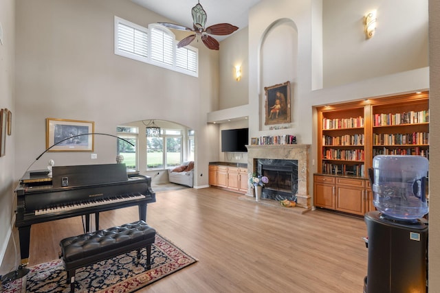 1124 Willowood Cir, Gulf Breeze, FL 32563 - living room featuring baseboards, a high ceiling, a ceiling fan, a fireplace, and light wood finished floors
