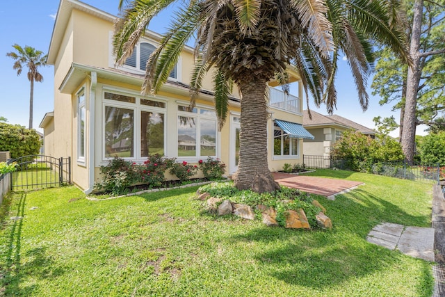 1124 Willowood Cir, Gulf Breeze, FL 32563 - back of house with a balcony, stucco siding, a gate, fence, and a lawn