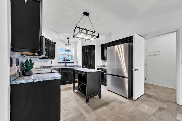 133 Wild Horse Dr, Crestview, FL 32536 - kitchen with freestanding refrigerator, dark cabinetry, backsplash, a kitchen island, and hanging light fixtures