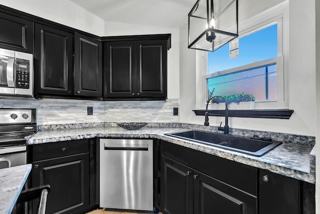 133 Wild Horse Dr, Crestview, FL 32536 - kitchen with dark cabinetry, appliances with stainless steel finishes, a sink, decorative backsplash, and a textured ceiling
