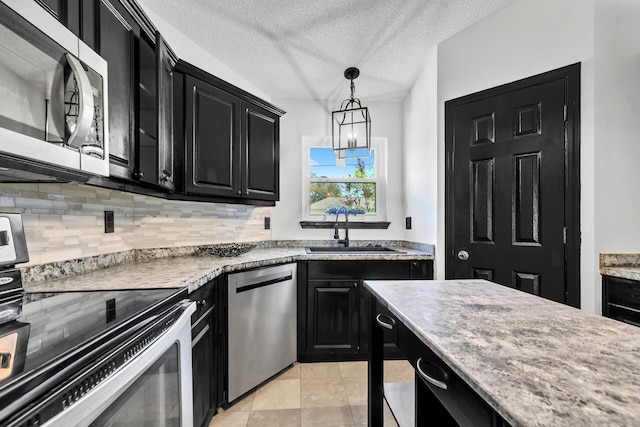 133 Wild Horse Dr, Crestview, FL 32536 - kitchen with dark cabinetry, appliances with stainless steel finishes, a sink, tasteful backsplash, and decorative light fixtures
