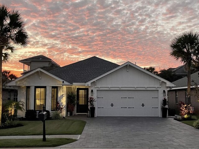 52 Secret Harbor Dr, Miramar Beach, FL 32550 - single story home featuring a garage, decorative driveway, board and batten siding, roof with shingles, and a lawn
