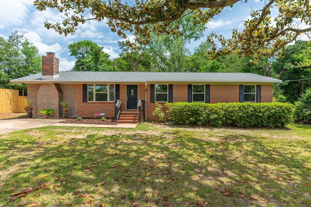 single story home with brick siding, fence, a chimney, and a front lawn
