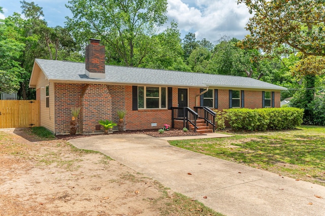 ranch-style home featuring brick siding, roof with shingles, fence, and a chimney