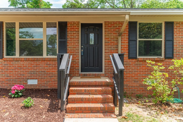 view of exterior entry with brick siding and crawl space