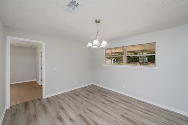 unfurnished room featuring an inviting chandelier, baseboards, wood finished floors, and visible vents