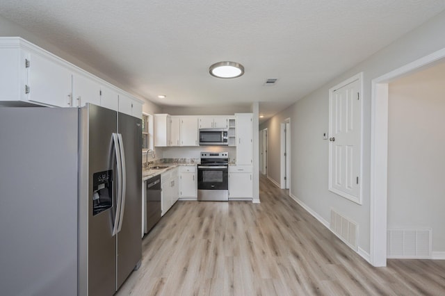 kitchen featuring a sink, appliances with stainless steel finishes, light wood-type flooring, and visible vents
