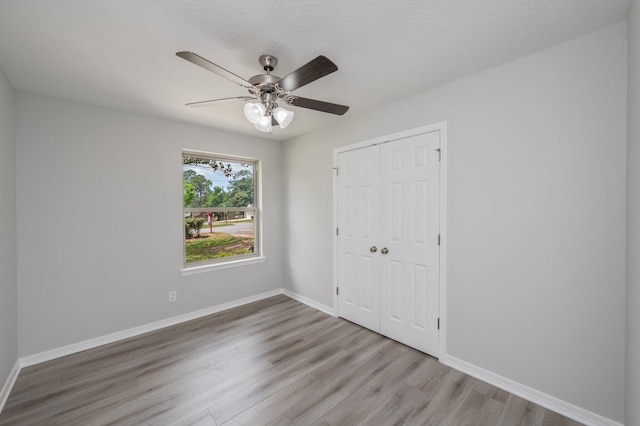 unfurnished bedroom with baseboards, wood finished floors, and a closet