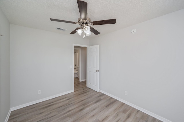 spare room featuring visible vents, a textured ceiling, baseboards, and light wood-type flooring