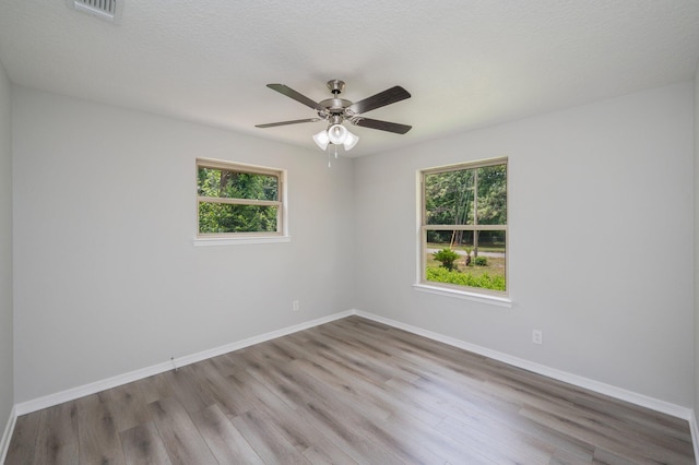 unfurnished room featuring visible vents, a wealth of natural light, and wood finished floors