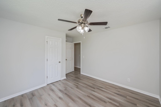 unfurnished bedroom featuring visible vents, light wood-style floors, baseboards, a textured ceiling, and a ceiling fan
