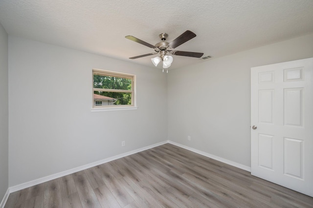unfurnished room featuring baseboards, ceiling fan, visible vents, and wood finished floors