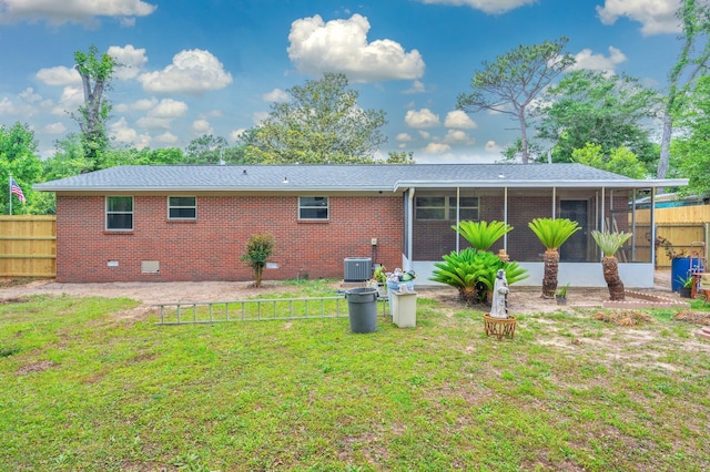 back of property with fence, central AC, brick siding, a sunroom, and a lawn