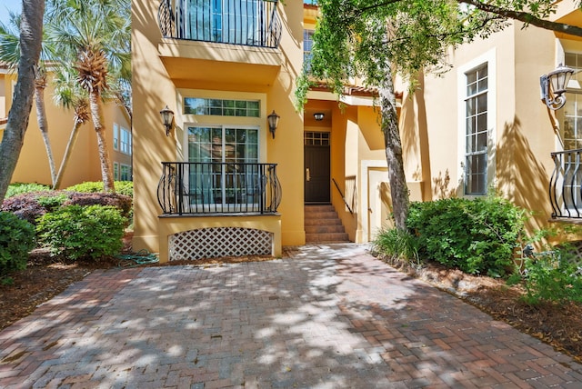 property entrance featuring stucco siding and a balcony