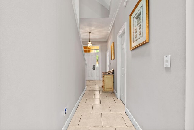 hallway with light tile patterned floors, baseboards, and crown molding