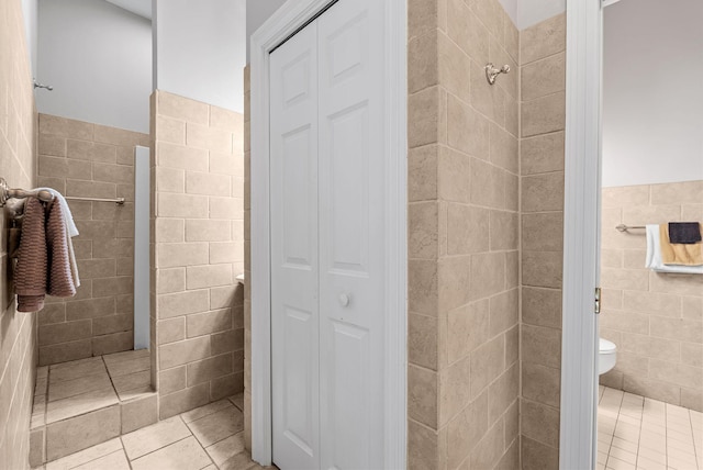 full bath with a closet, toilet, a walk in shower, and tile walls