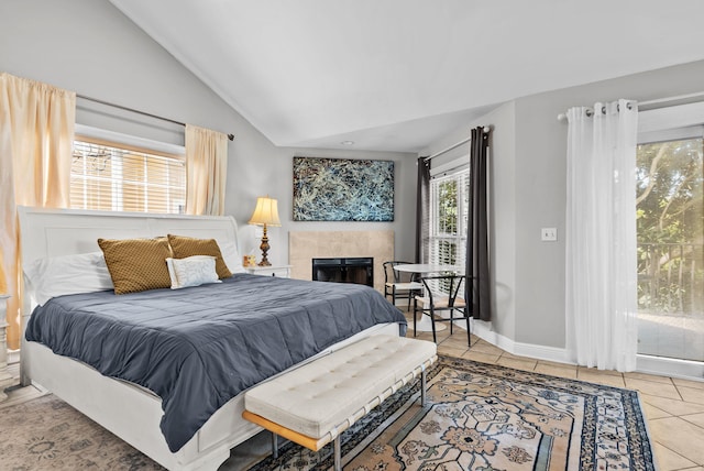 tiled bedroom featuring baseboards, a tile fireplace, and lofted ceiling