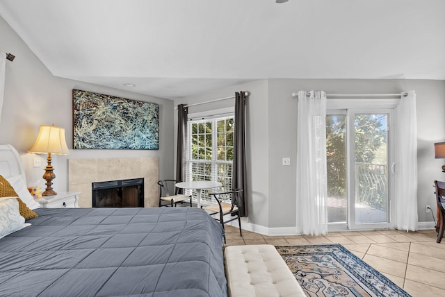 bedroom with baseboards, access to outside, tile patterned flooring, and a fireplace