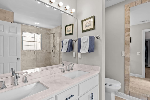 full bathroom with a sink, a tile shower, baseboards, and toilet
