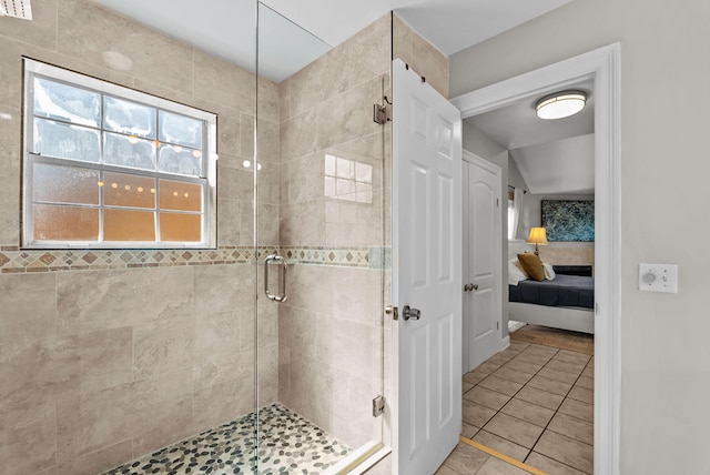 ensuite bathroom featuring a stall shower, ensuite bath, and tile patterned floors
