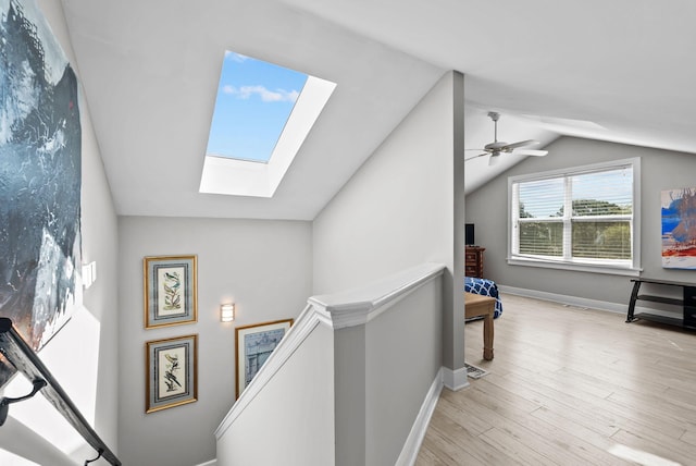 additional living space with vaulted ceiling with skylight, baseboards, a ceiling fan, and wood finished floors