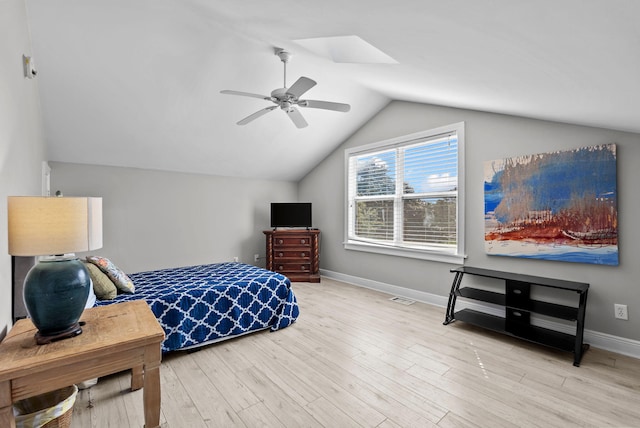 bedroom with baseboards, vaulted ceiling with skylight, visible vents, ceiling fan, and wood finished floors