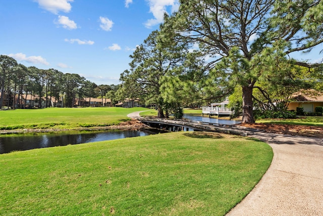 surrounding community with a water view and a yard