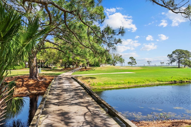surrounding community with a water view and a lawn