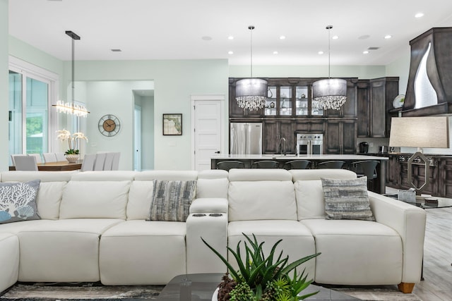 living room with recessed lighting, a notable chandelier, light wood-type flooring, and visible vents