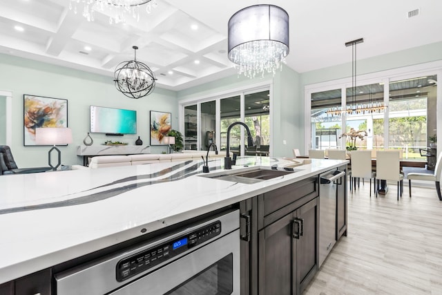 kitchen with a chandelier, open floor plan, dishwasher, and a sink