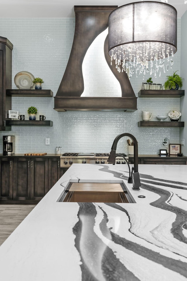 kitchen with custom range hood, backsplash, open shelves, and dark brown cabinetry