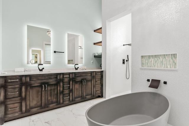 full bath with double vanity, a freestanding tub, marble finish floor, and a sink