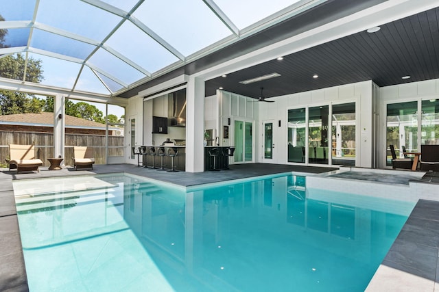 view of swimming pool with a patio area, ceiling fan, glass enclosure, outdoor dry bar, and a fenced in pool