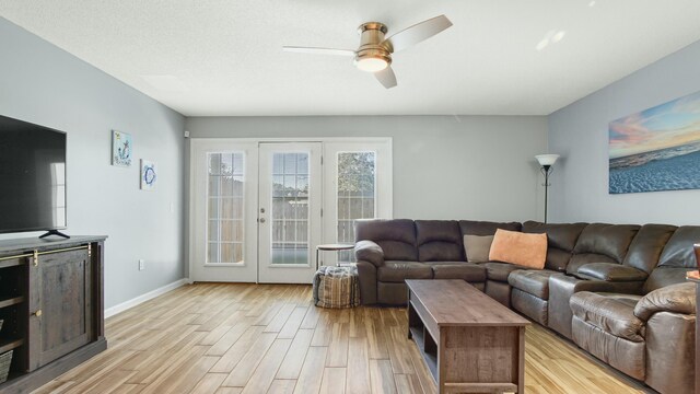 living area with light wood-style flooring, a ceiling fan, and baseboards