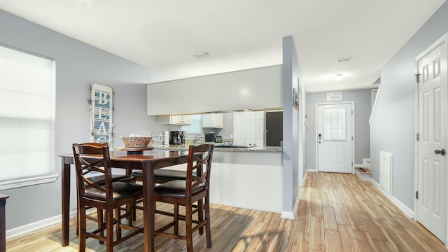 dining space with light wood-type flooring and baseboards
