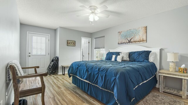 bedroom featuring a textured ceiling, wood finished floors, baseboards, and a ceiling fan