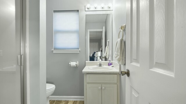 bathroom featuring toilet, baseboards, vanity, and wood finished floors