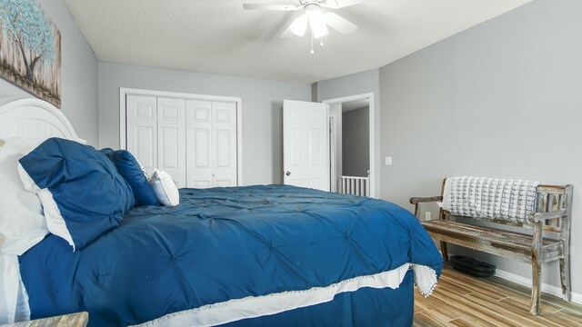 bedroom featuring a closet, baseboards, a ceiling fan, a textured ceiling, and wood finished floors