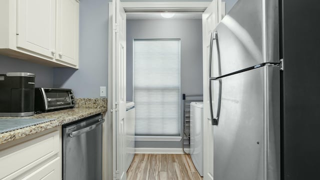 kitchen with light stone counters, a toaster, white cabinetry, light wood-style floors, and appliances with stainless steel finishes