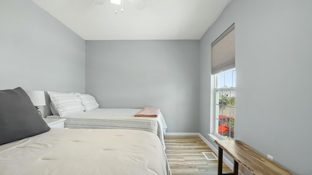bedroom featuring light wood finished floors, visible vents, baseboards, and ceiling fan