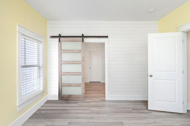 3120 Pinot Way, Crestview, FL 32536 - unfurnished bedroom featuring baseboards, a barn door, wooden walls, and wood finished floors