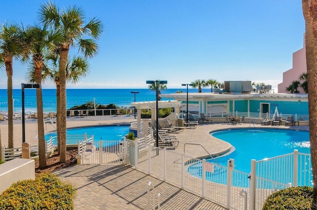 pool with a water view, a patio, fence, and a gate
