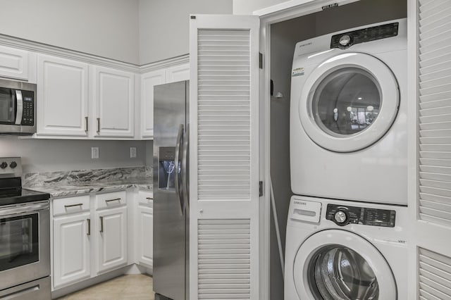 washroom featuring stacked washer / drying machine, light tile patterned floors, and laundry area